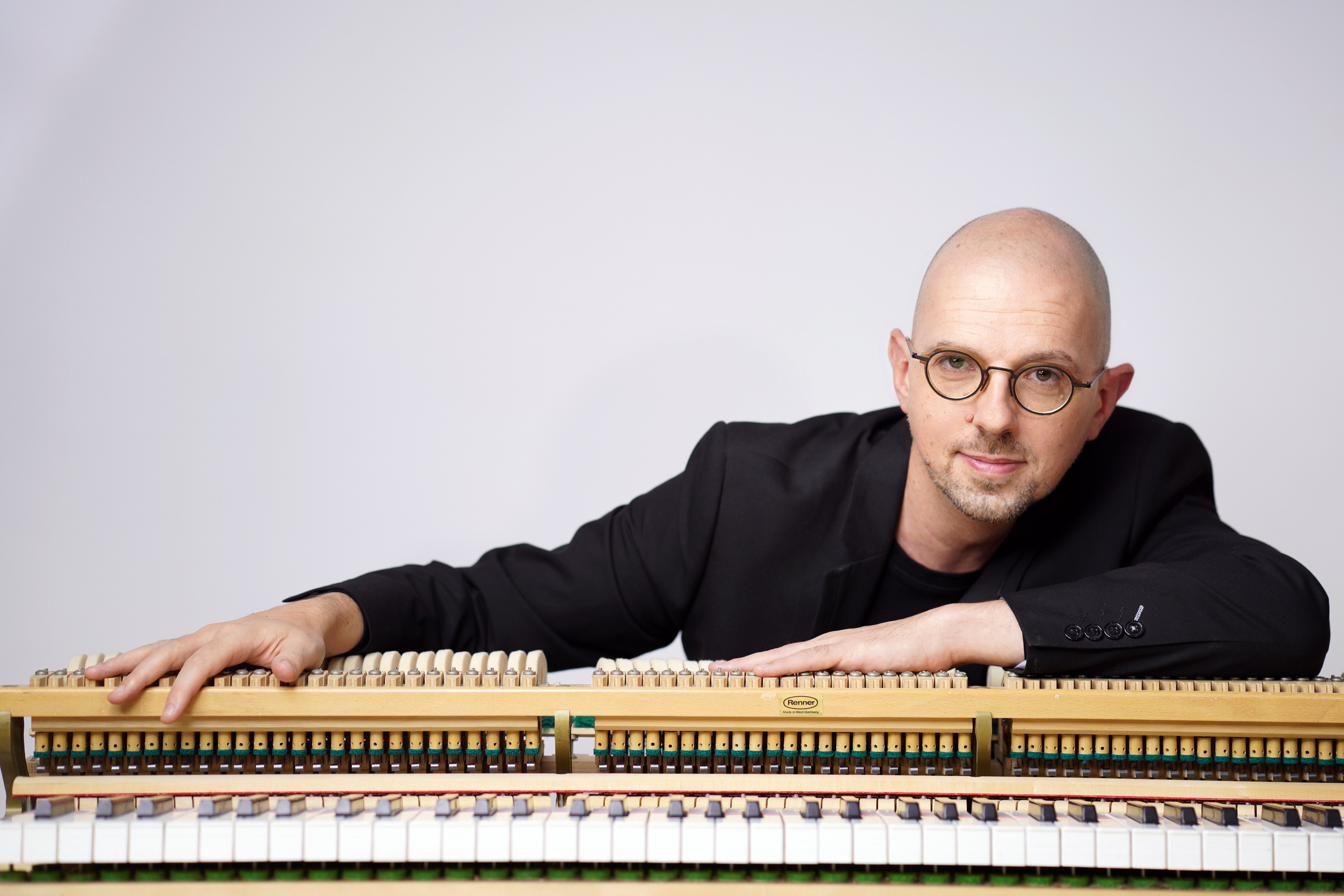 Michaël Ertzscheid accoudé à la mécanique d’un piano