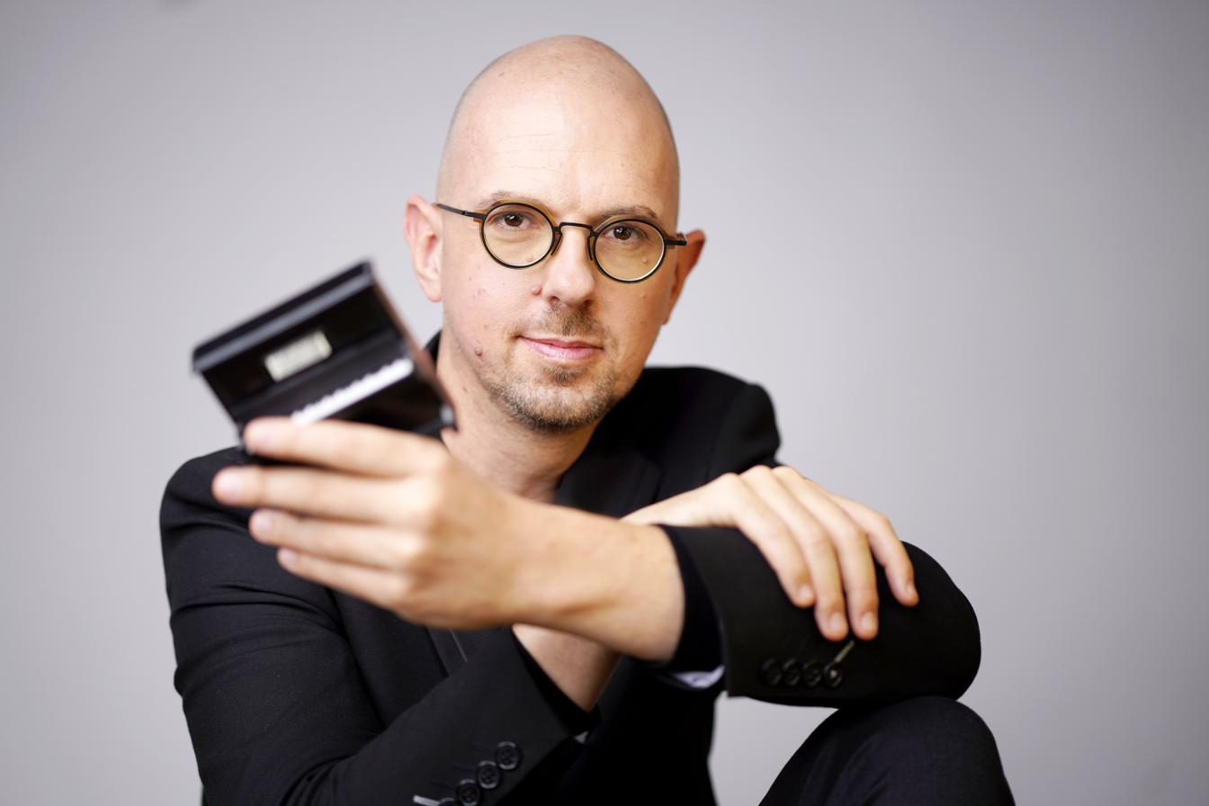 Michaël Ertzscheid tenant un toy piano à bout de bras